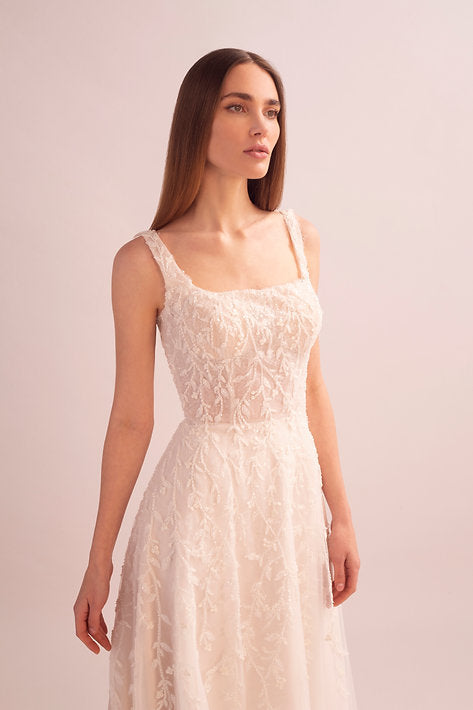 Woman wearing a white lace dress against a light pink background