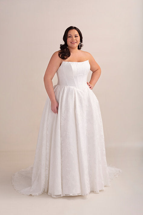 Woman wearing a strapless white wedding dress on a beige background