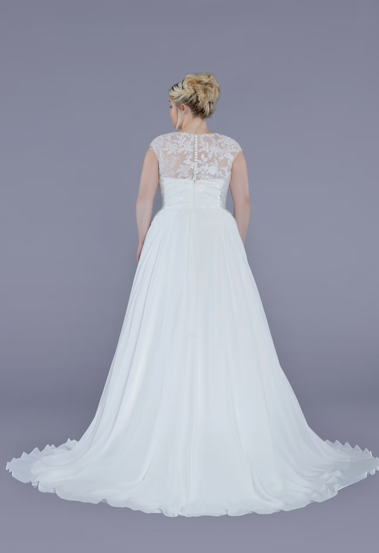 White wedding dress with lace detailing on a plain background