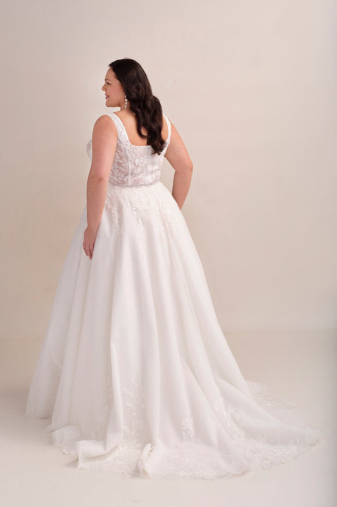 Woman wearing a white wedding dress against a plain background