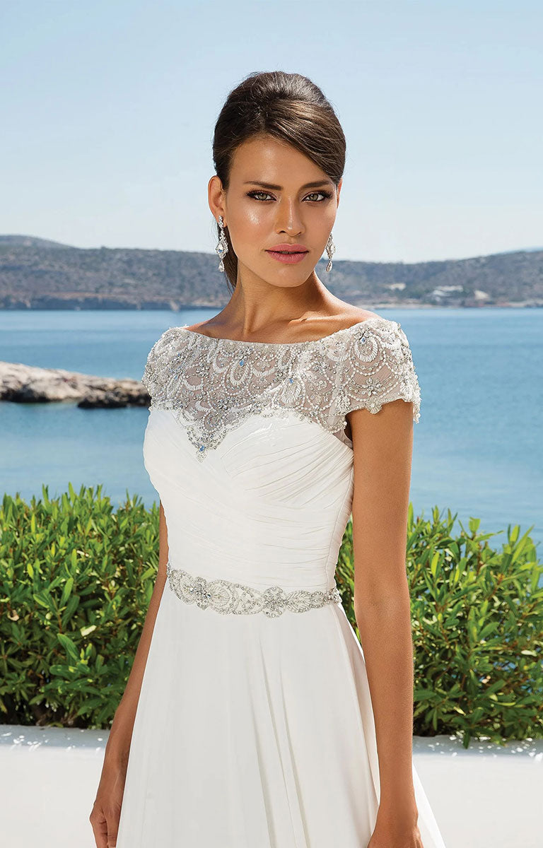 Woman wearing 8799 by Justin Alexander - Chiffon Ball Gown with Beaded Portrait Neckline with lace details by the sea.