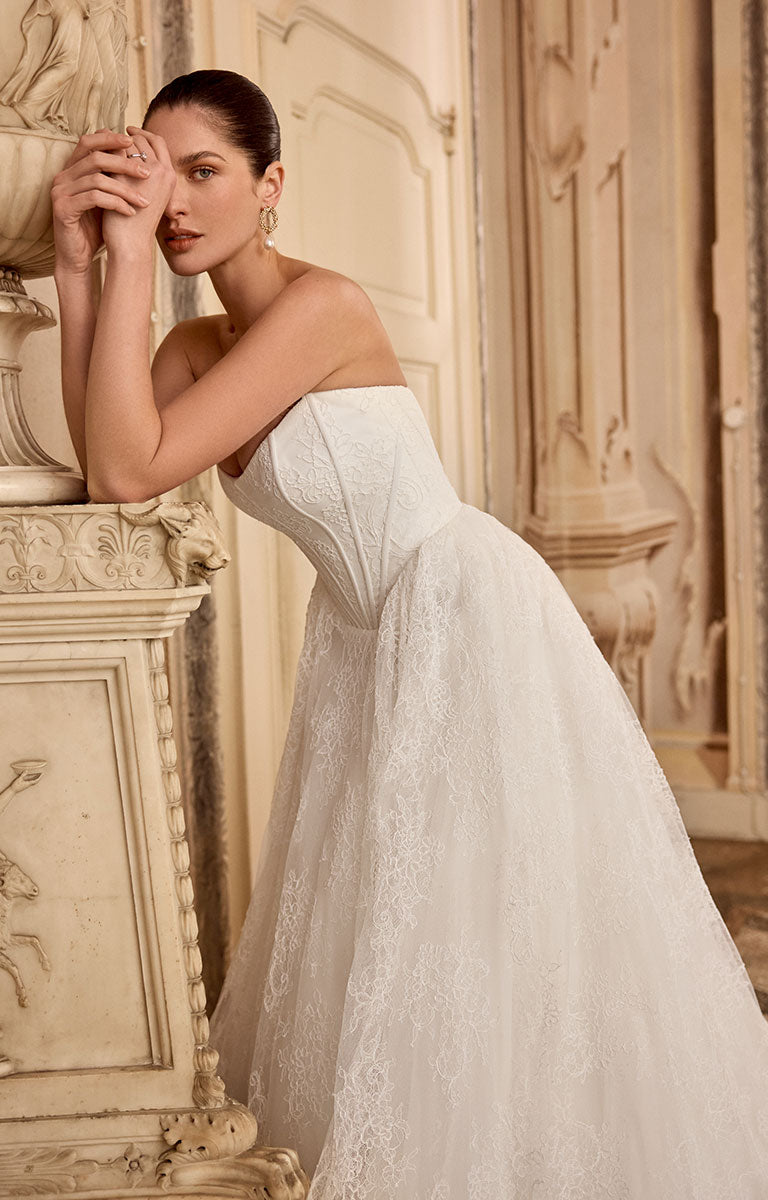 Woman in Leighton 88468 by Justin Alexander - Corded Lace A-Line Wedding Dress with Basque Waist standing in an ornate room.