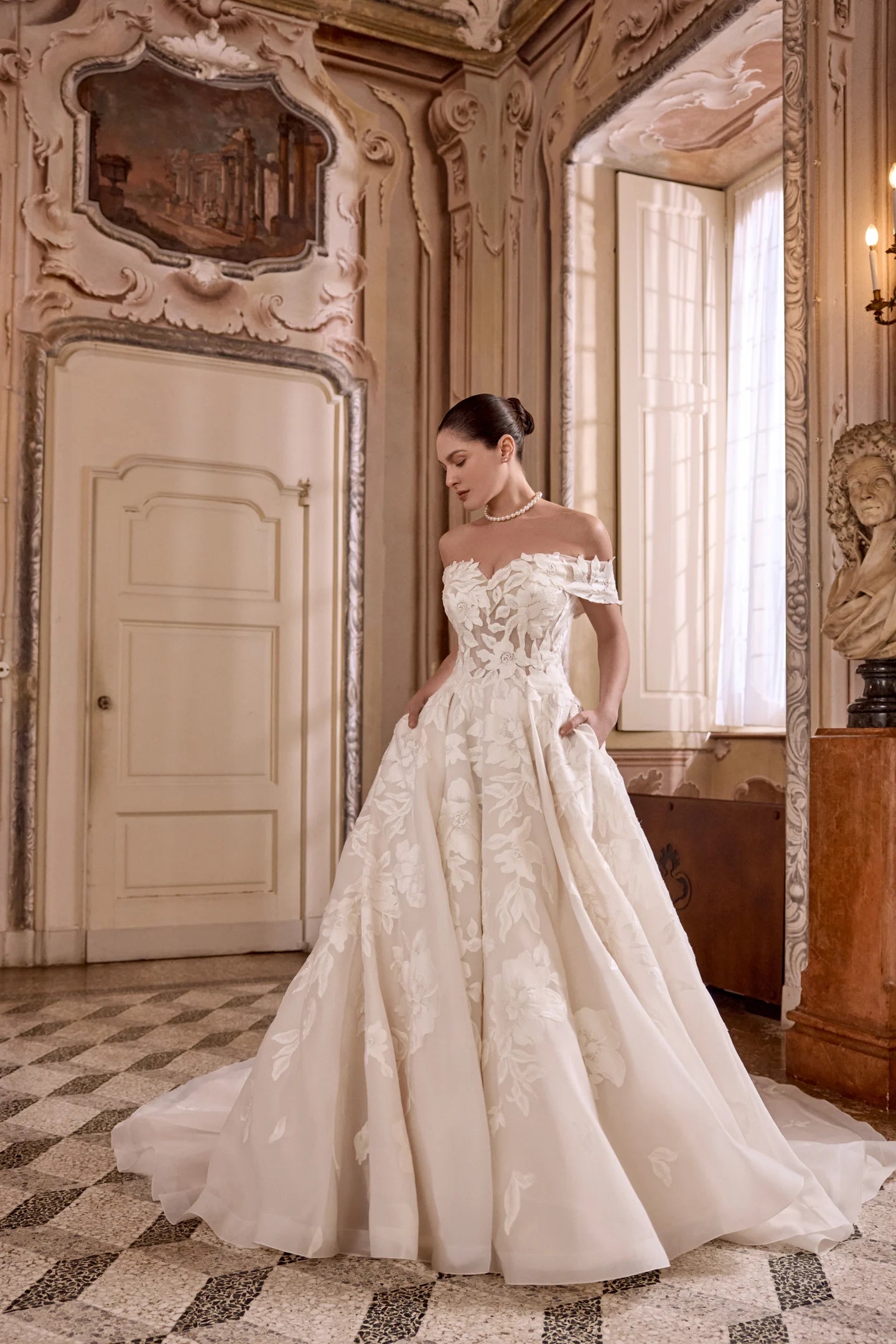 Woman in a white wedding dress standing in an ornate room.