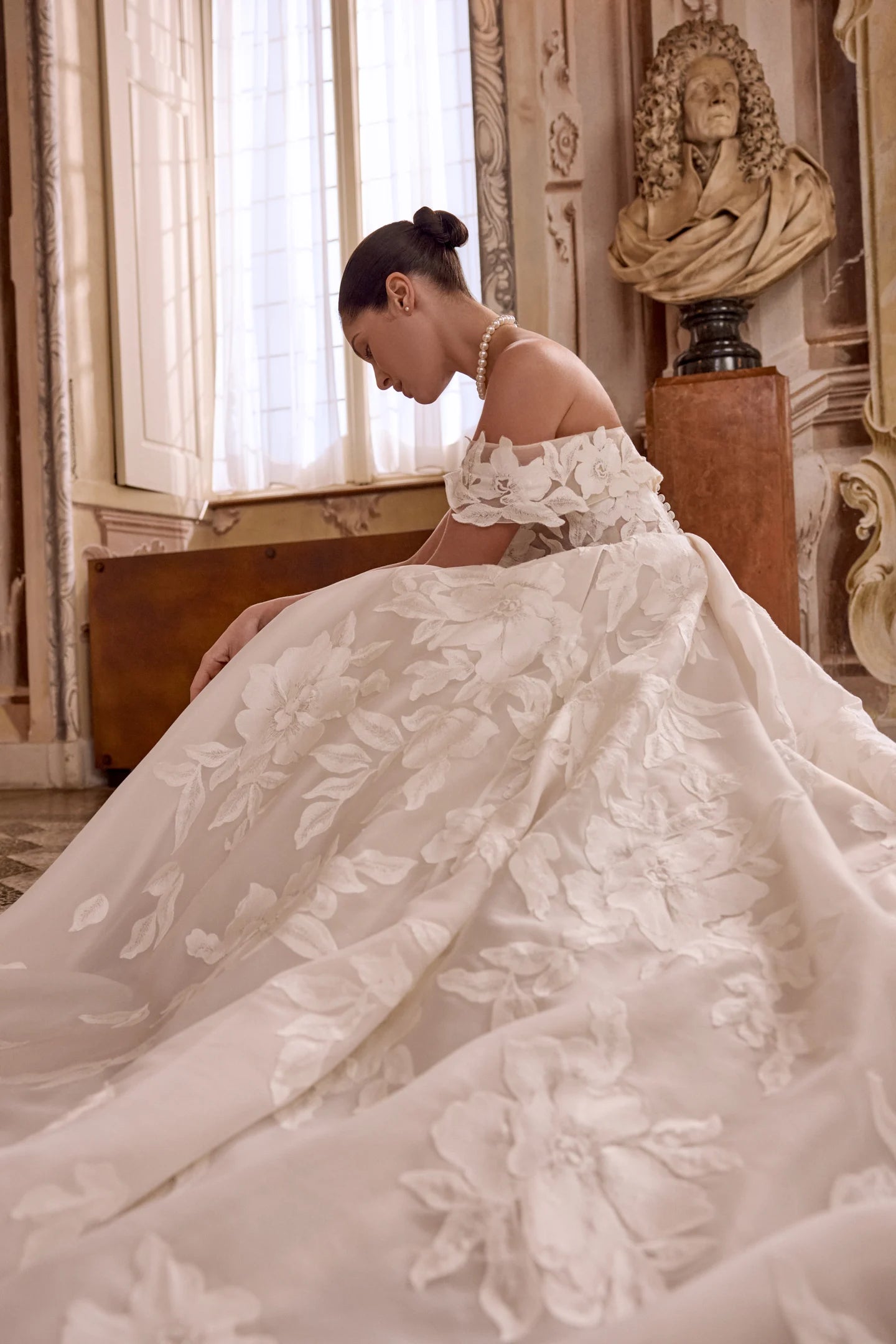 Woman in a white wedding dress with floral details in an elegant room.