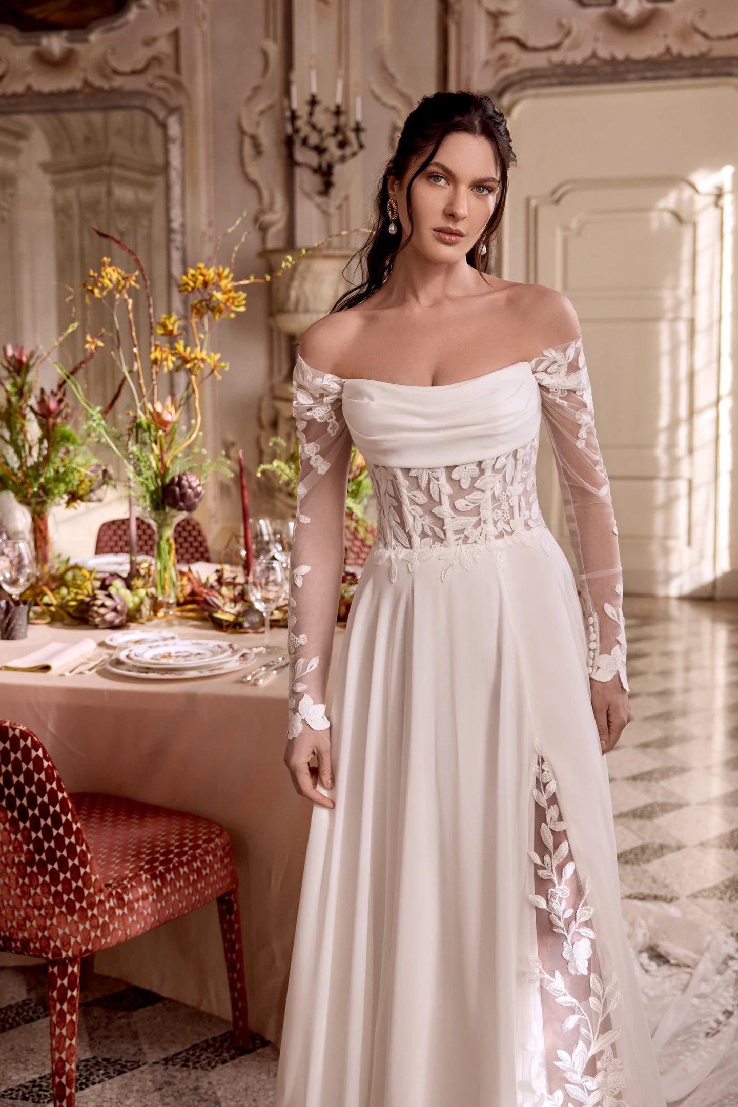 Woman in a white wedding dress with lace sleeves in an elegant room.