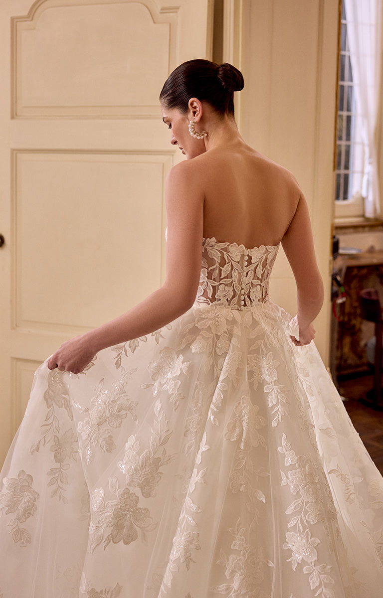 Woman wearing a white lace wedding dress in an elegant indoor setting.