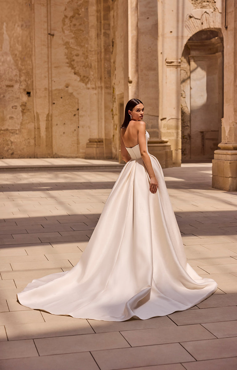 Woman in a white wedding dress standing in an ancient stone courtyard.