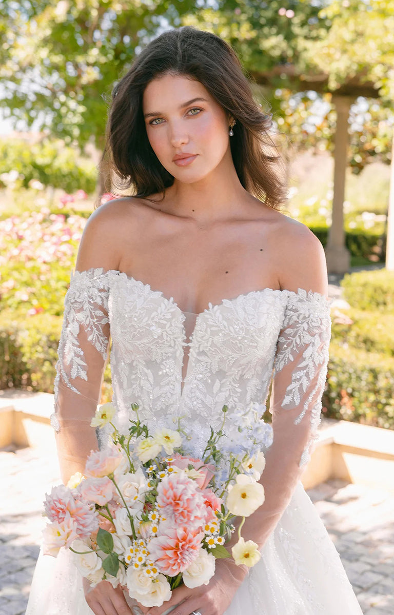 Woman in A1418 by Allure Bridals - Beaded Lace Ball Gown Wedding Dress with Glitter Tulle holding a bouquet of flowers outdoors.