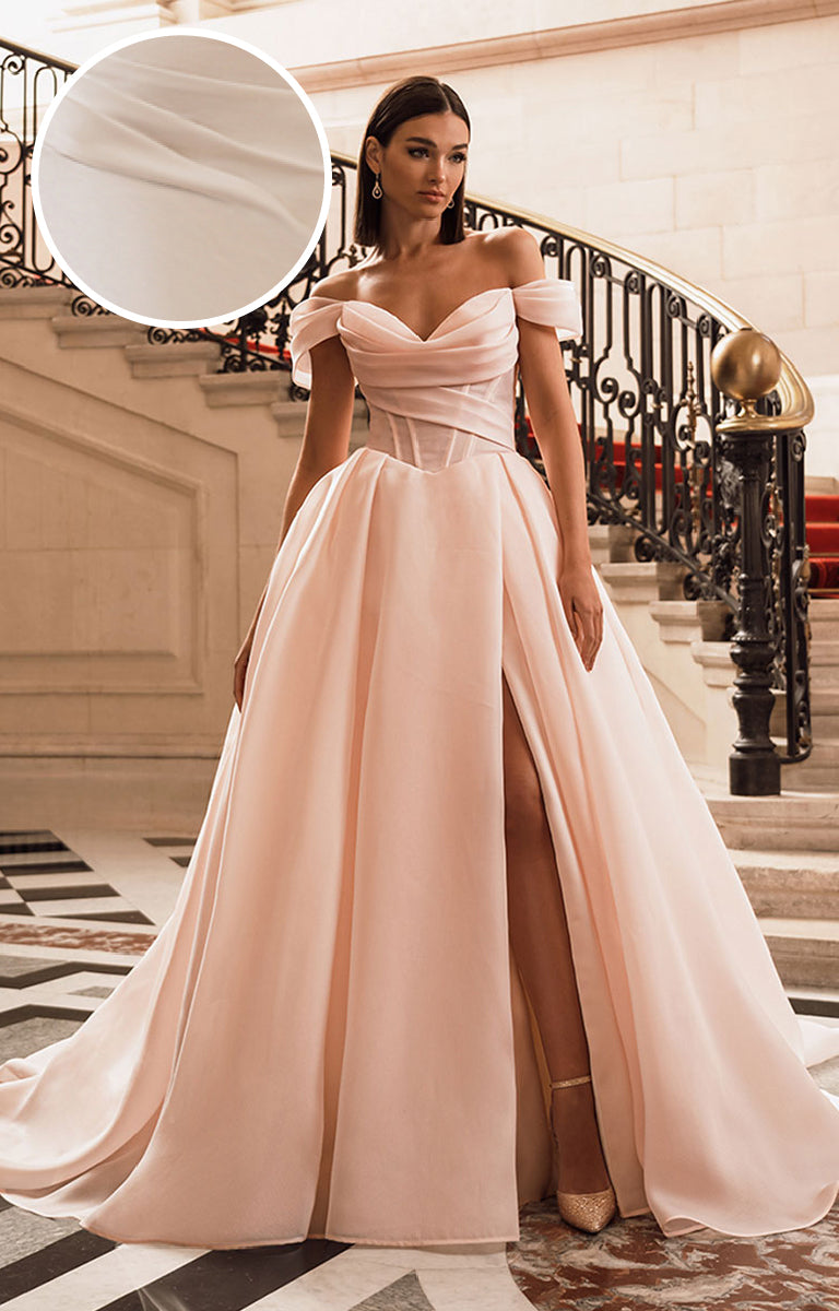 Woman in a Filippa Wedding Dress by Elysee - it is a strapless gown with a thigh length slit and she is standing in an elegant interior setting.