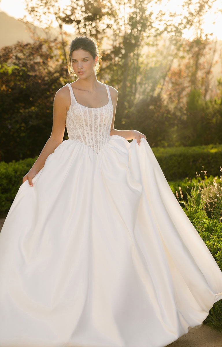 Woman in a Woman wearing A1406 by Allure Bridal from Abella - Beaded Lace and Satin Ball Gown Wedding Dress standing outdoors with greenery in the background