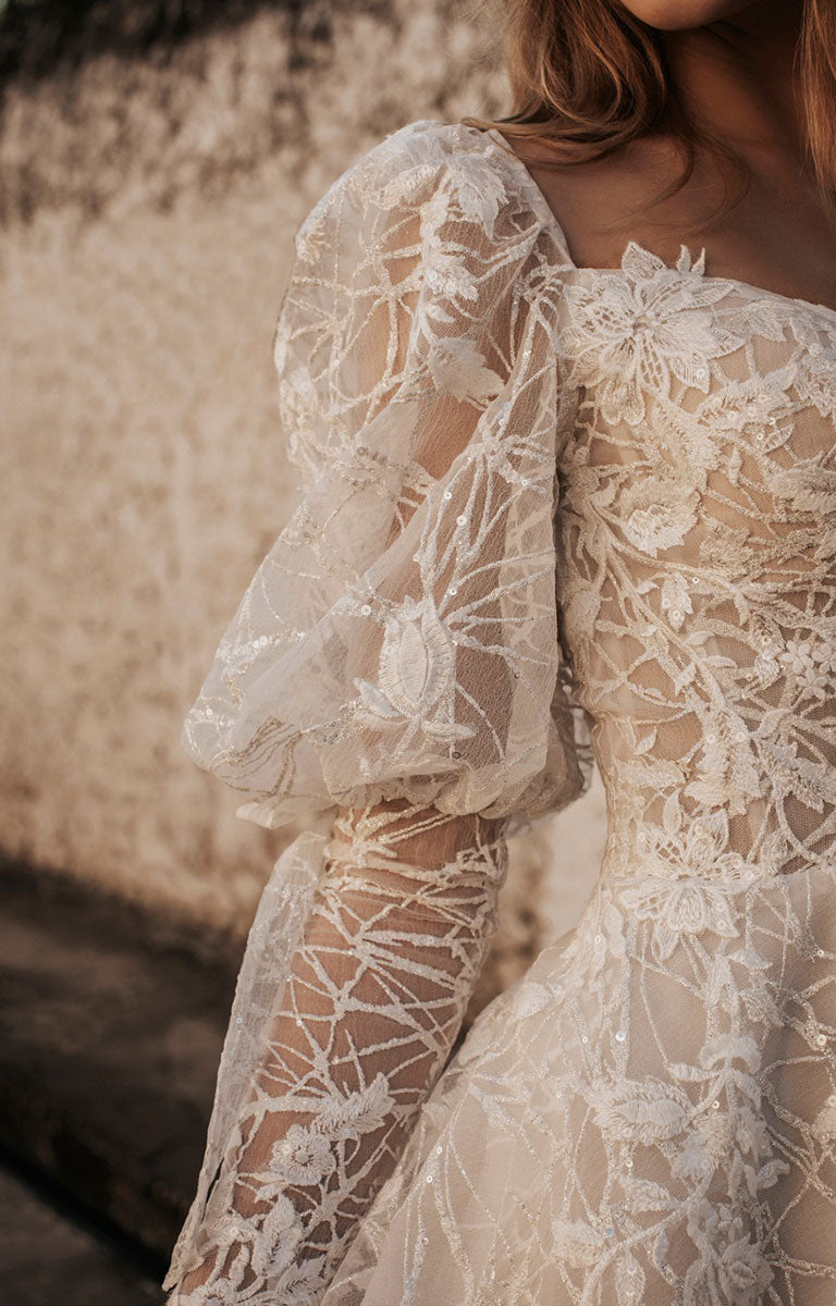 Close-up of a lace dress with floral patterns against a blurred natural background