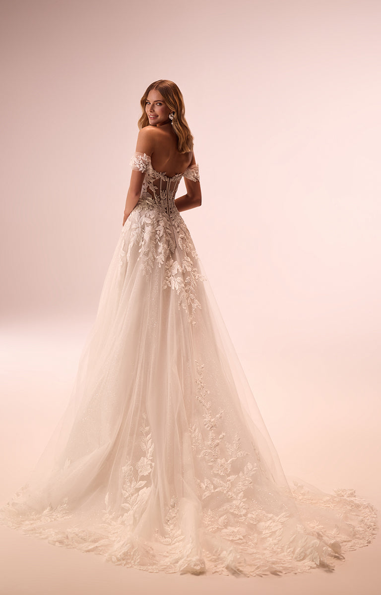 Woman wearing a white wedding dress with floral details on a soft pink background