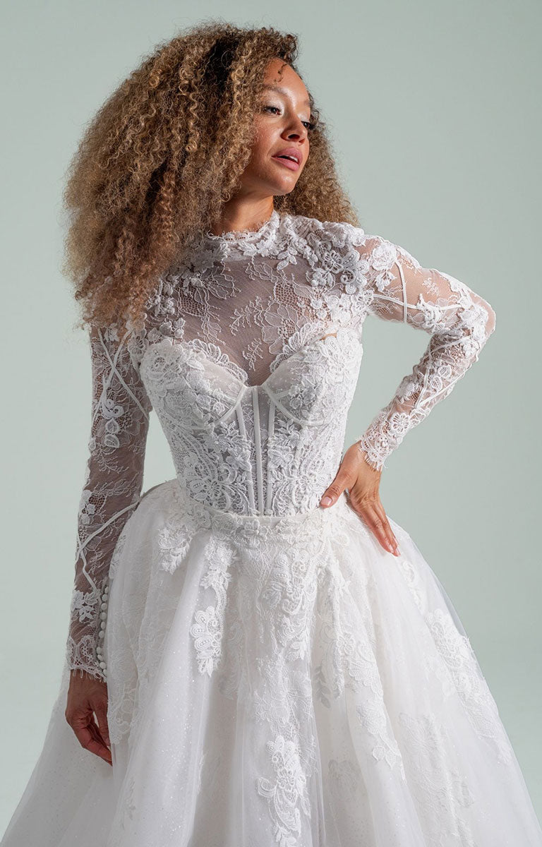Woman wearing Becoming Jane by Hayley Paige - Convertible Lace Fit-and-Flare Wedding Dress with Tulle Overskirt against a light gray background