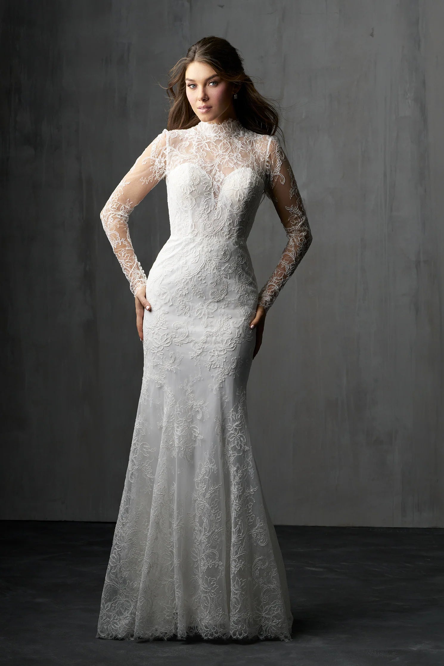 Woman wearing a lace wedding dress against a gray background