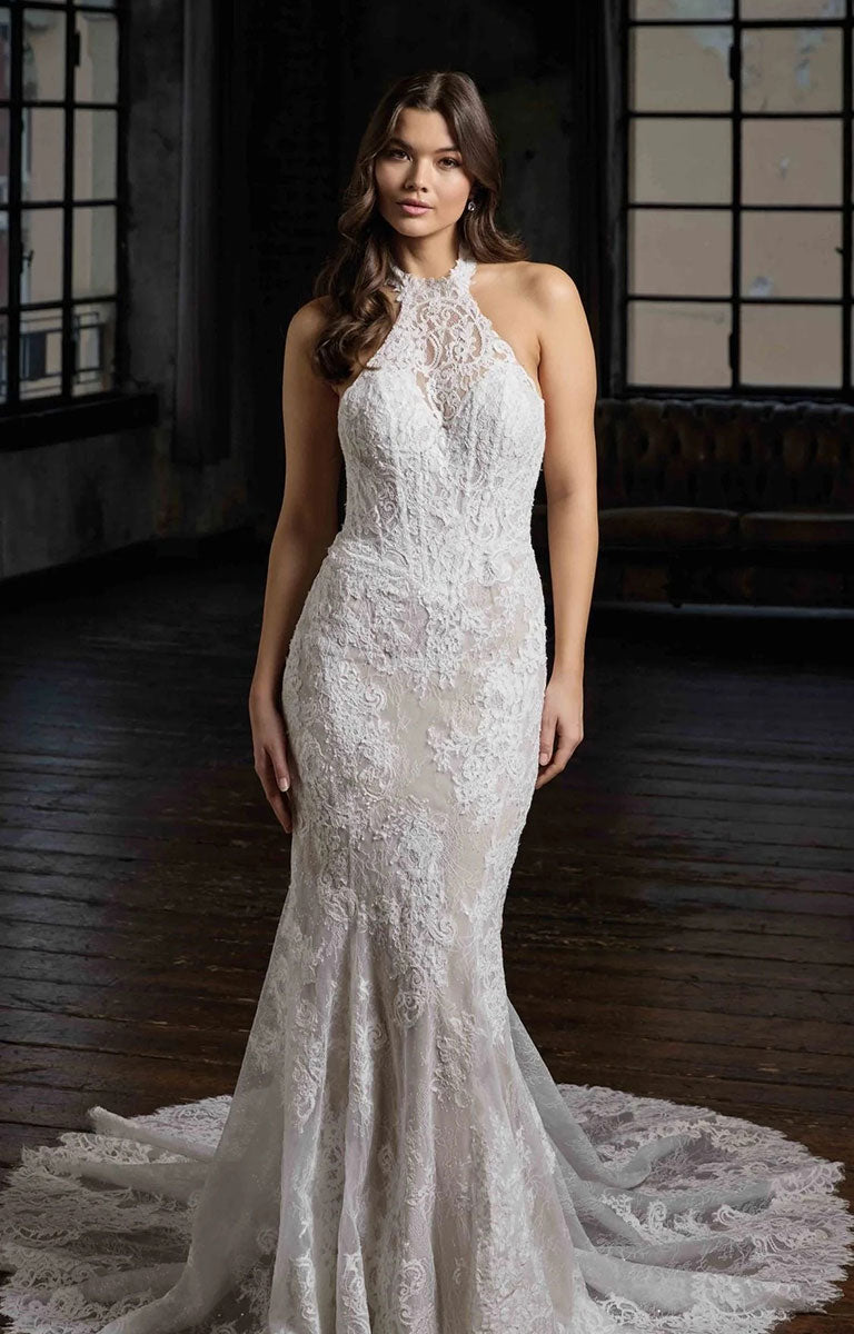 A woman modeling Pascale CT748 by Eddy K Milano Couture - Lace Fit-and-Flare Wedding Dress with Halter Neckline in a dimly lit indoor studio with dark wood floors and large window panes.