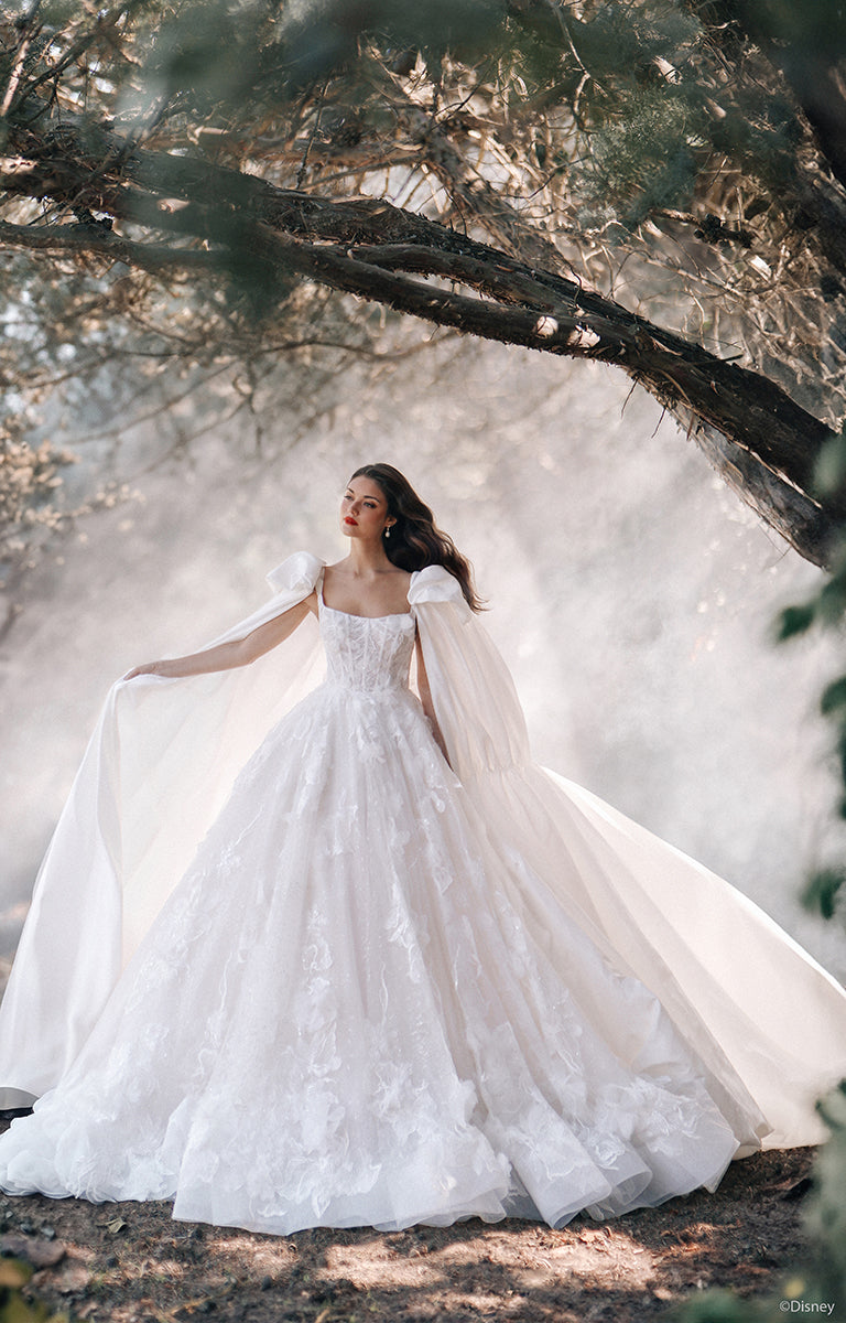 Woman in D447 Snow White - Disney Fairytale Weddings Wedding Dress standing in a forest with misty background