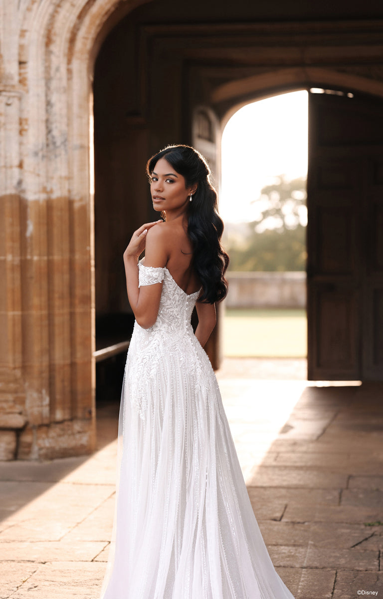 Woman wearing D474 Jasmine - Disney Fairytale Weddings Wedding Dress outside a grand country house. 