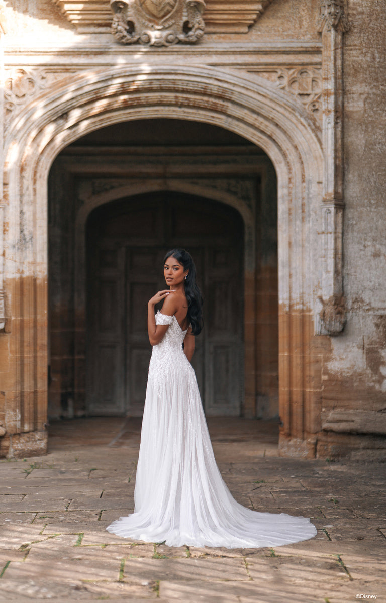 Woman wearing D474 Jasmine - Disney Fairytale Weddings Wedding Dress outside a grand country house. 