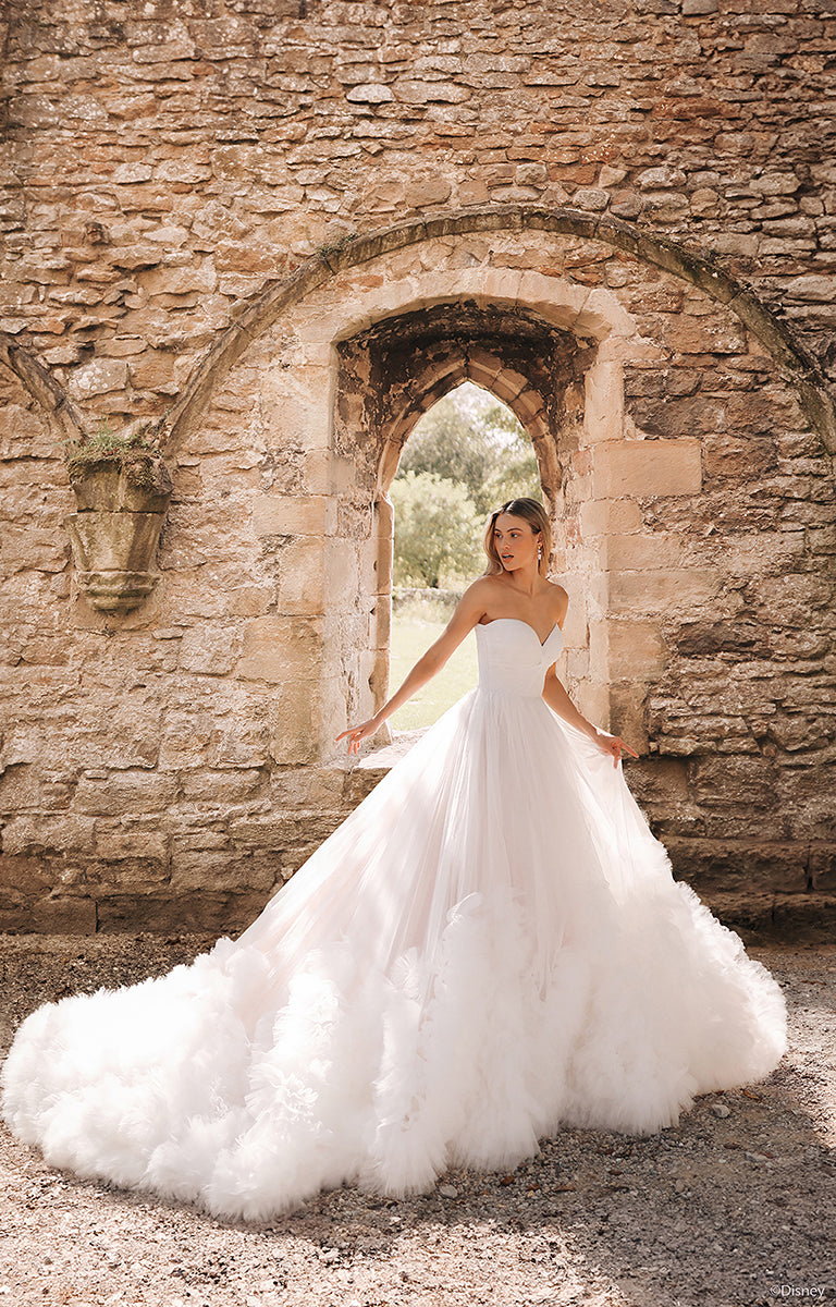 Woman in DP426 Rapunzel - Disney Fairytale Weddings Wedding Dress standing in front of stone archway.