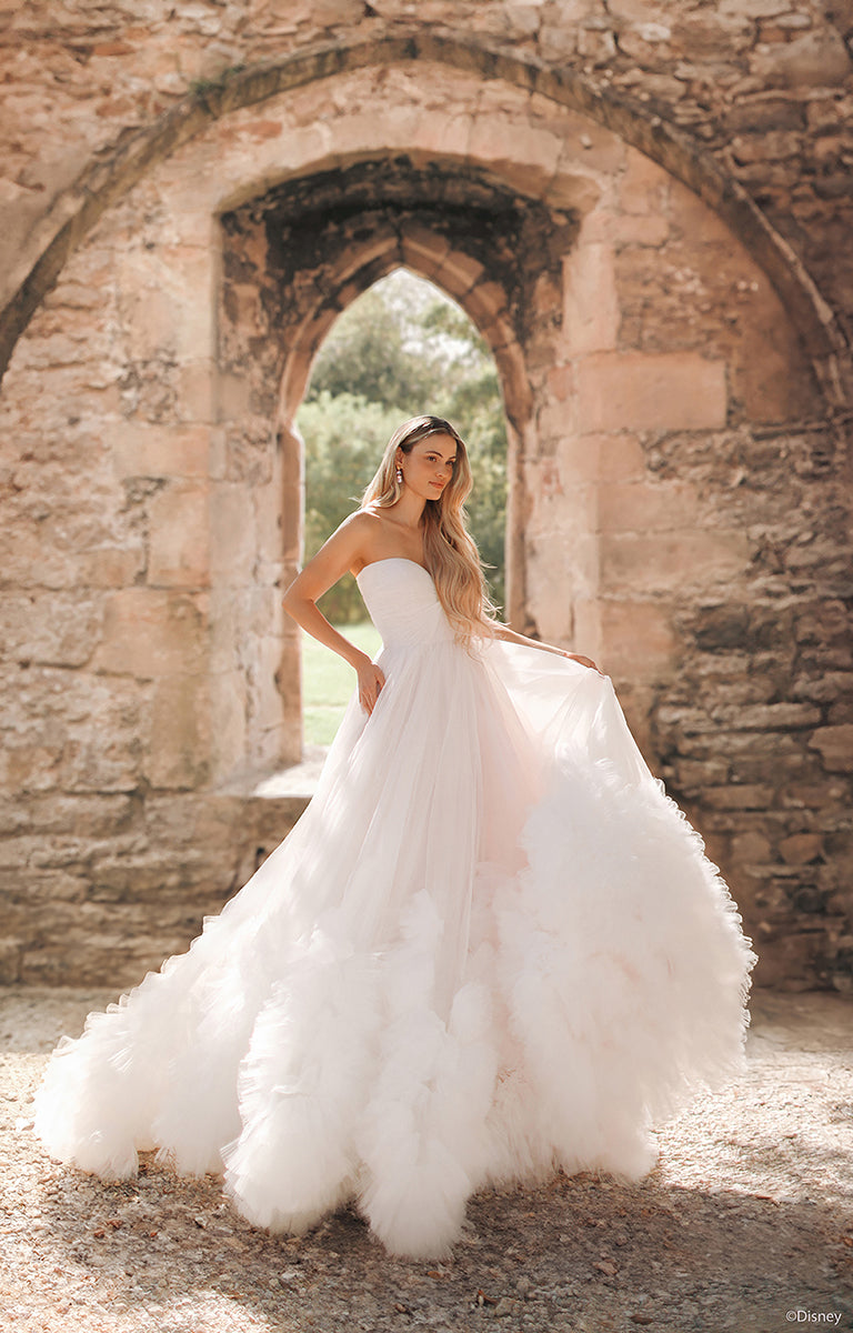 Woman in DP426 Rapunzel - Disney Fairytale Weddings Wedding Dress standing in front of stone ruins.