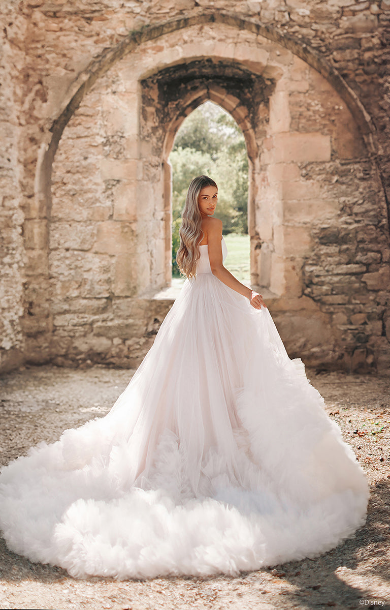 Woman in DP426 Rapunzel - Disney Fairytale Weddings Wedding Dress standing in front of stone ruins