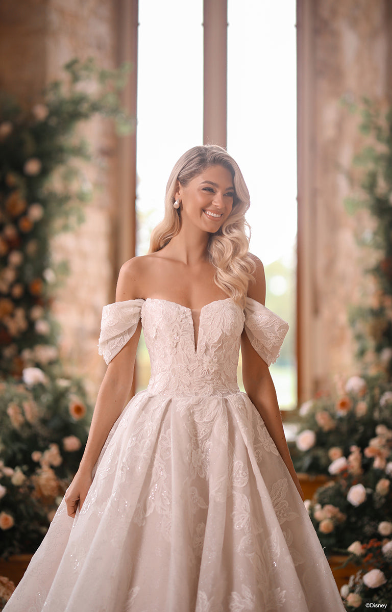 Woman wearing DP451 Sleeping Beauty - Disney Fairytale Weddings Wedding Dress with floral details in a decorated indoor setting.