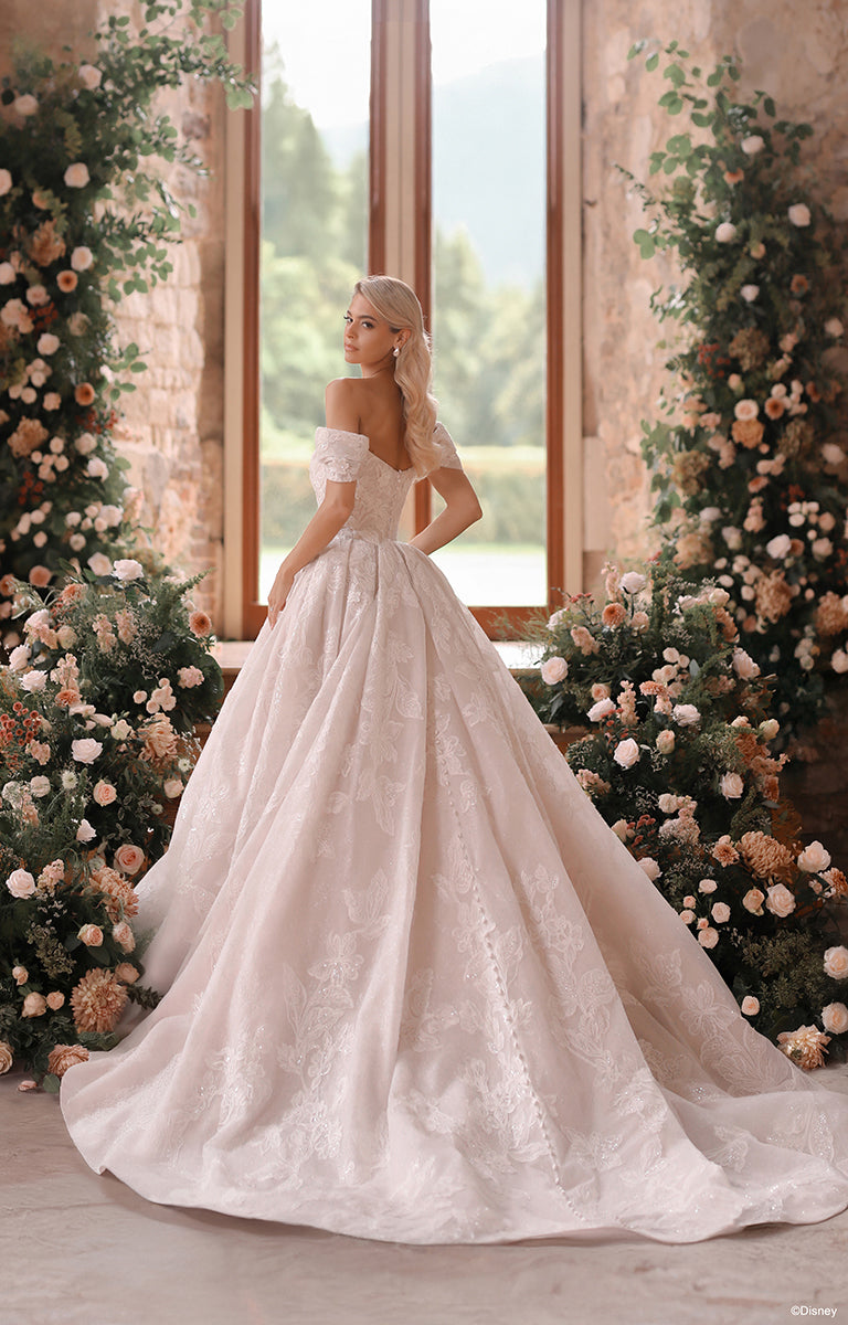 Woman in DP451 Sleeping Beauty - Disney Fairytale Weddings Wedding Dress standing in a decorated room with floral arrangements.