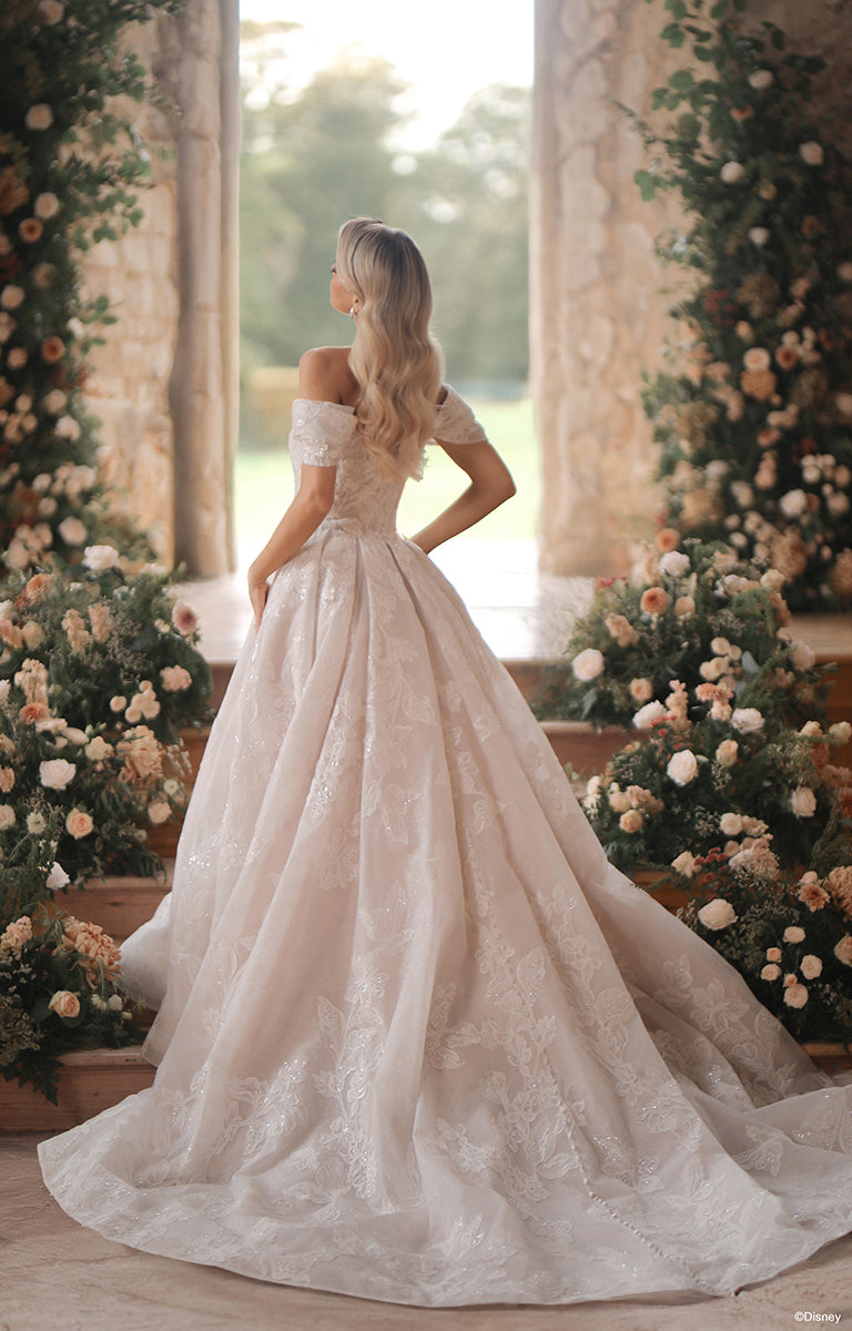 Woman in DP451 Sleeping Beauty - Disney Fairytale Weddings Wedding Dress standing in a decorated indoor setting with flowers.