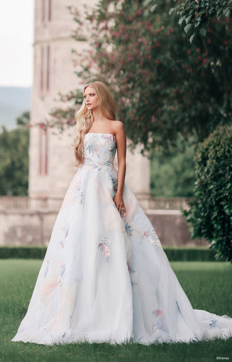 Woman wearing DP456 Rapunzel - Disney Fairytale Weddings Wedding Dress standing in the beautiful gardens of a castle.