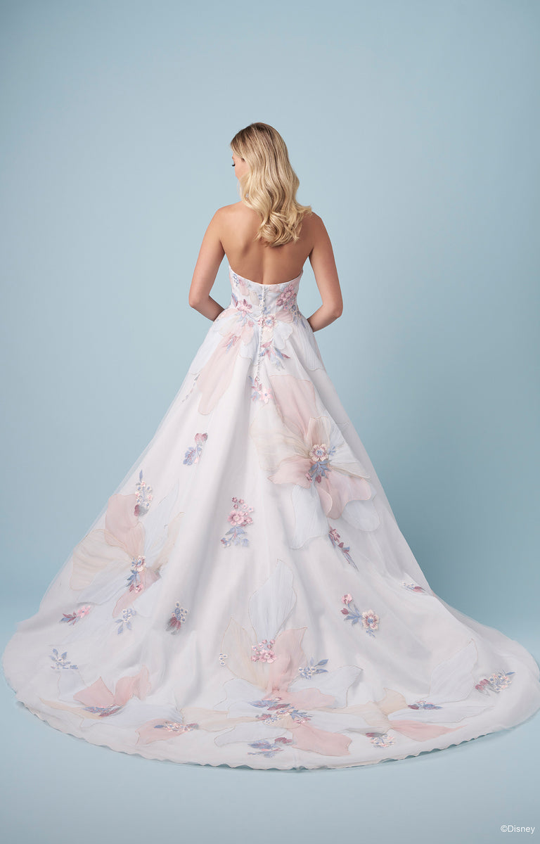 Woman showcasing the rear of the DP456 Rapunzel - Disney Fairytale Weddings Wedding Dress standing against a pale blue studio wall backdrop.