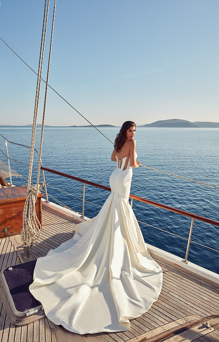 Woman in a white wedding dress standing on a boat with a scenic background