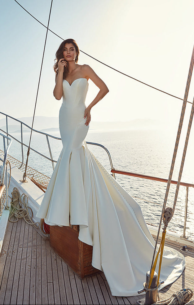 Woman in a white wedding dress standing on a boat with a scenic background