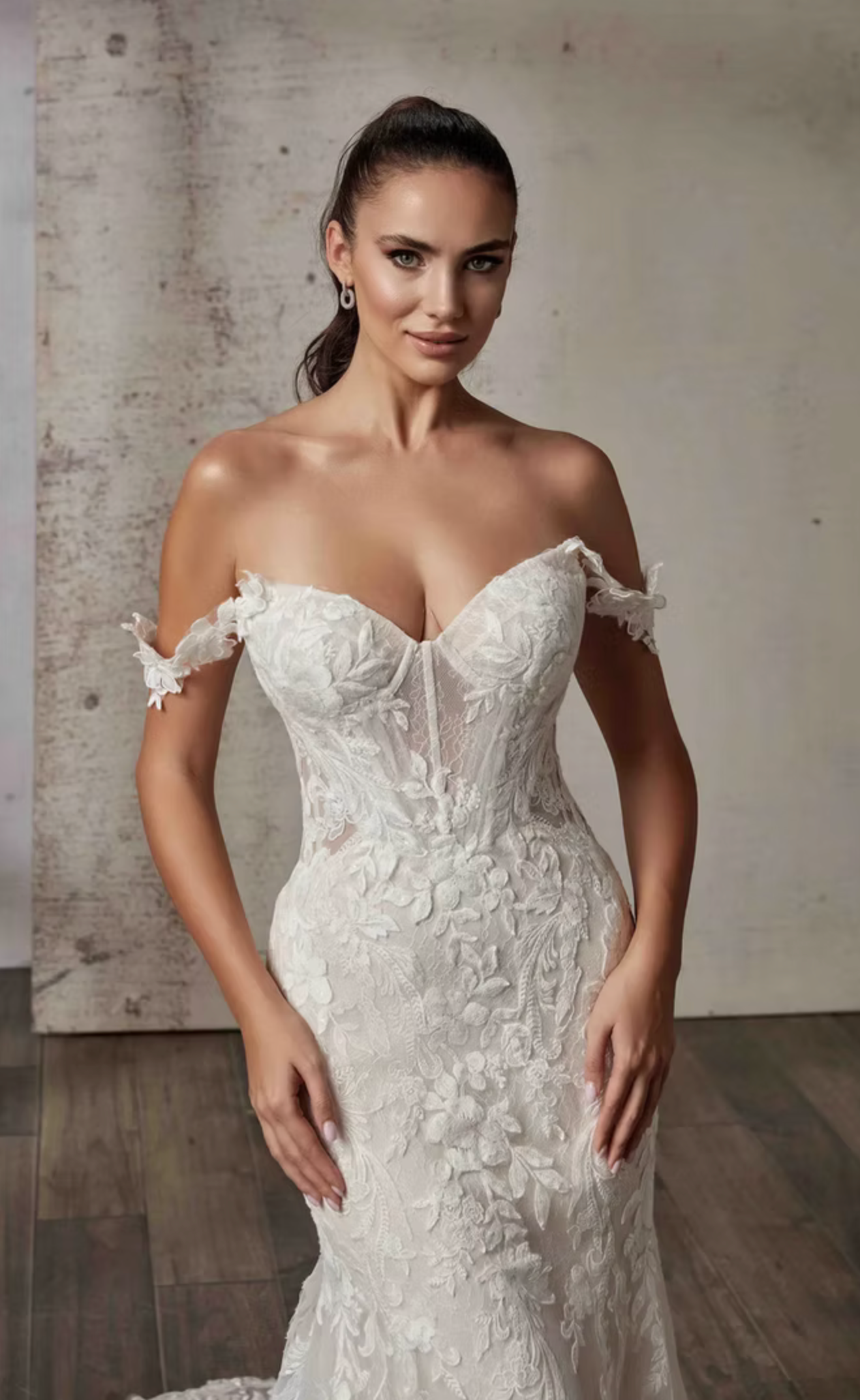 Woman wearing a white lace wedding dress against a neutral background