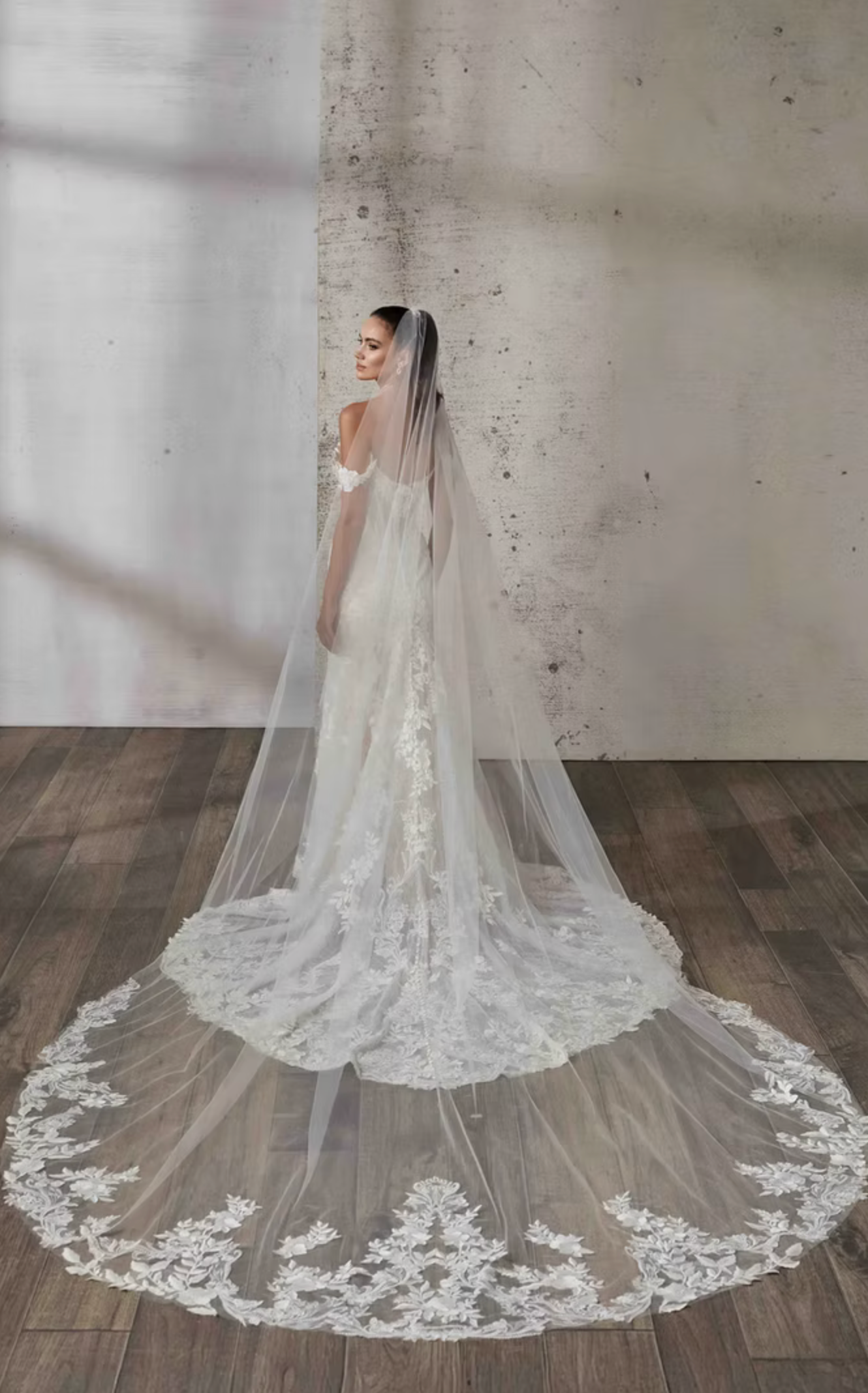 Elegant wedding veil with floral lace details on a wooden floor.