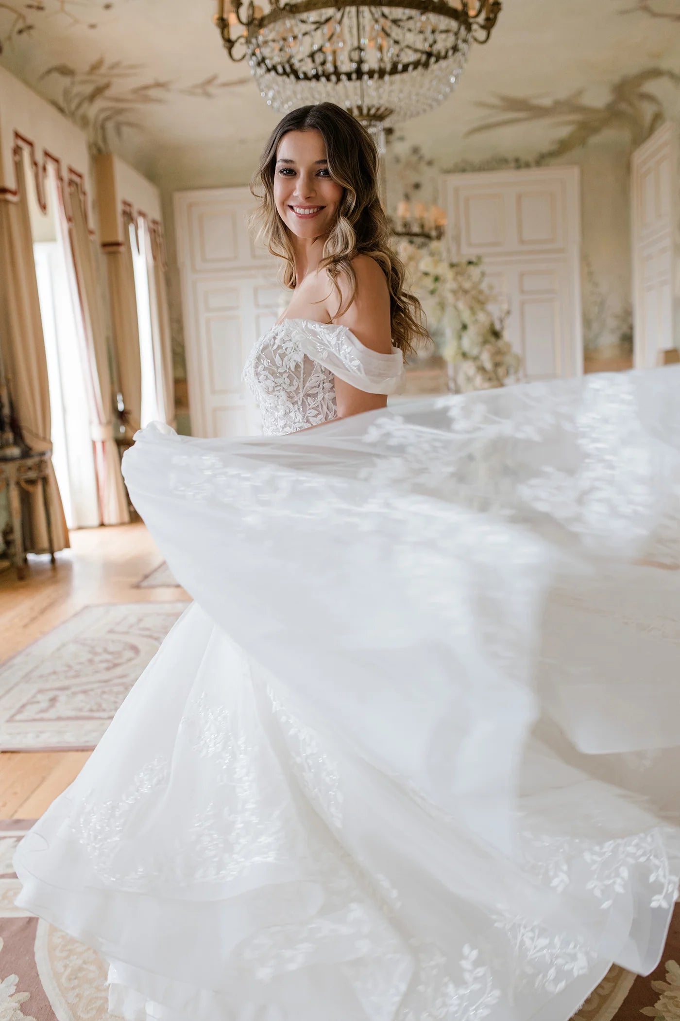 Woman in a white wedding dress standing in a elegant room with chandelier