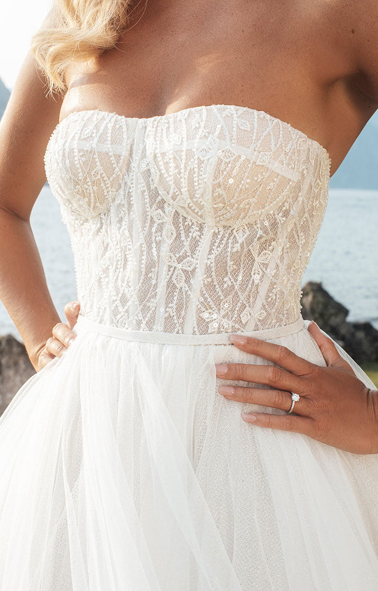 Woman wearing Stella E405 by Abella - Strapless Sparkle Tulle Ballgown Wedding Dress with a lake and mountain backdrop.
