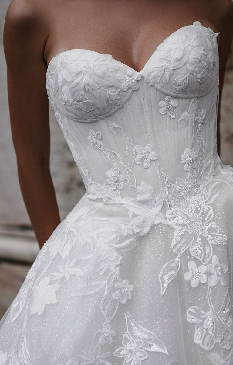 Close-up of a strapless wedding dress with floral lace details.