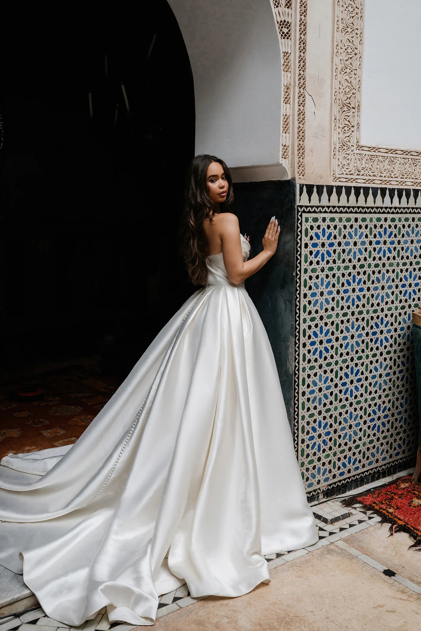 Woman in a white wedding dress standing in a decorative interior setting.