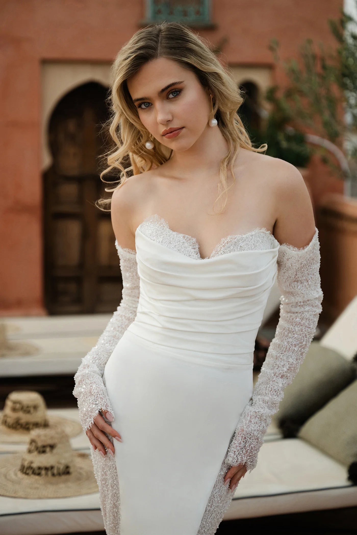 Woman in a white strapless dress with long sleeves standing outdoors.