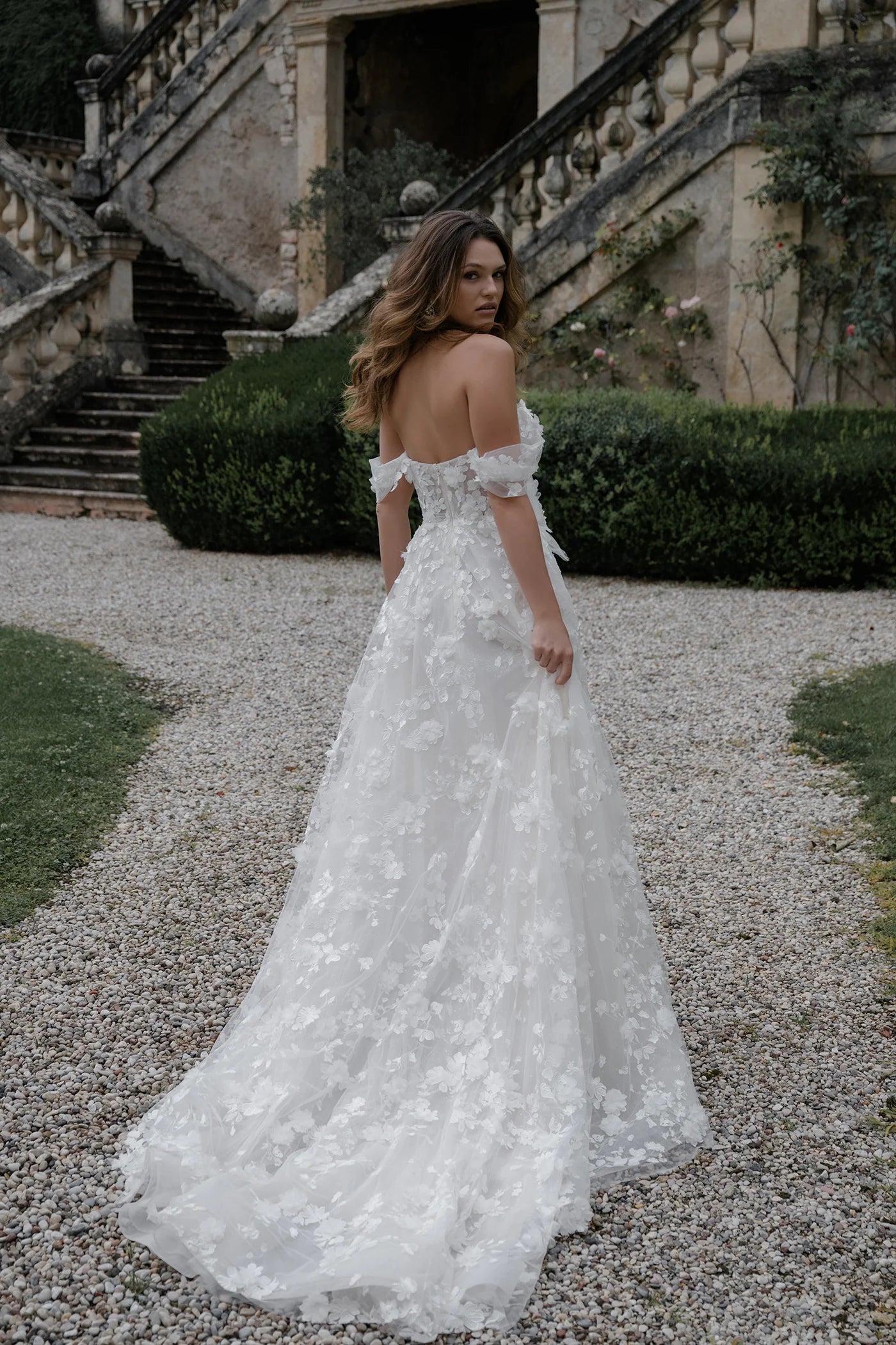 Woman in a white wedding dress standing in front of an elegant outdoor staircase.