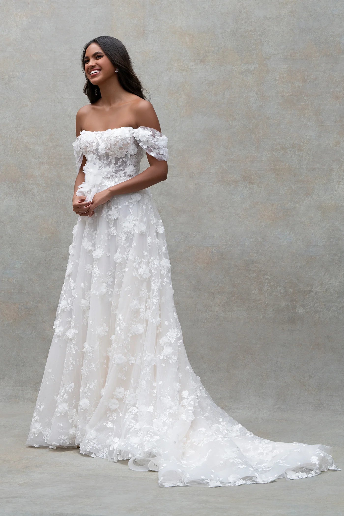 Woman wearing a white off-shoulder wedding dress against a neutral background
