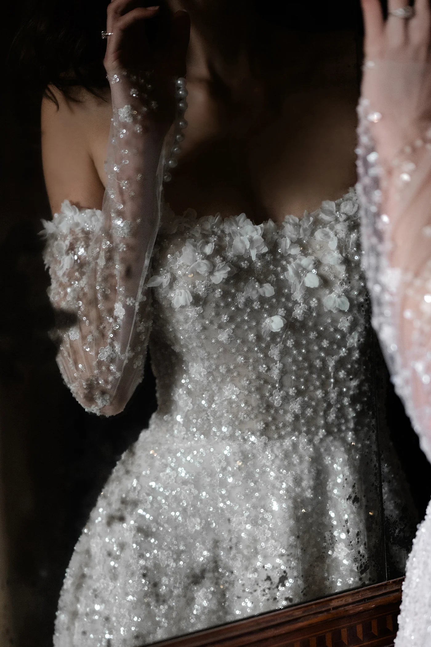 Person wearing a sparkling silver dress with long sleeves in front of a mirror.
