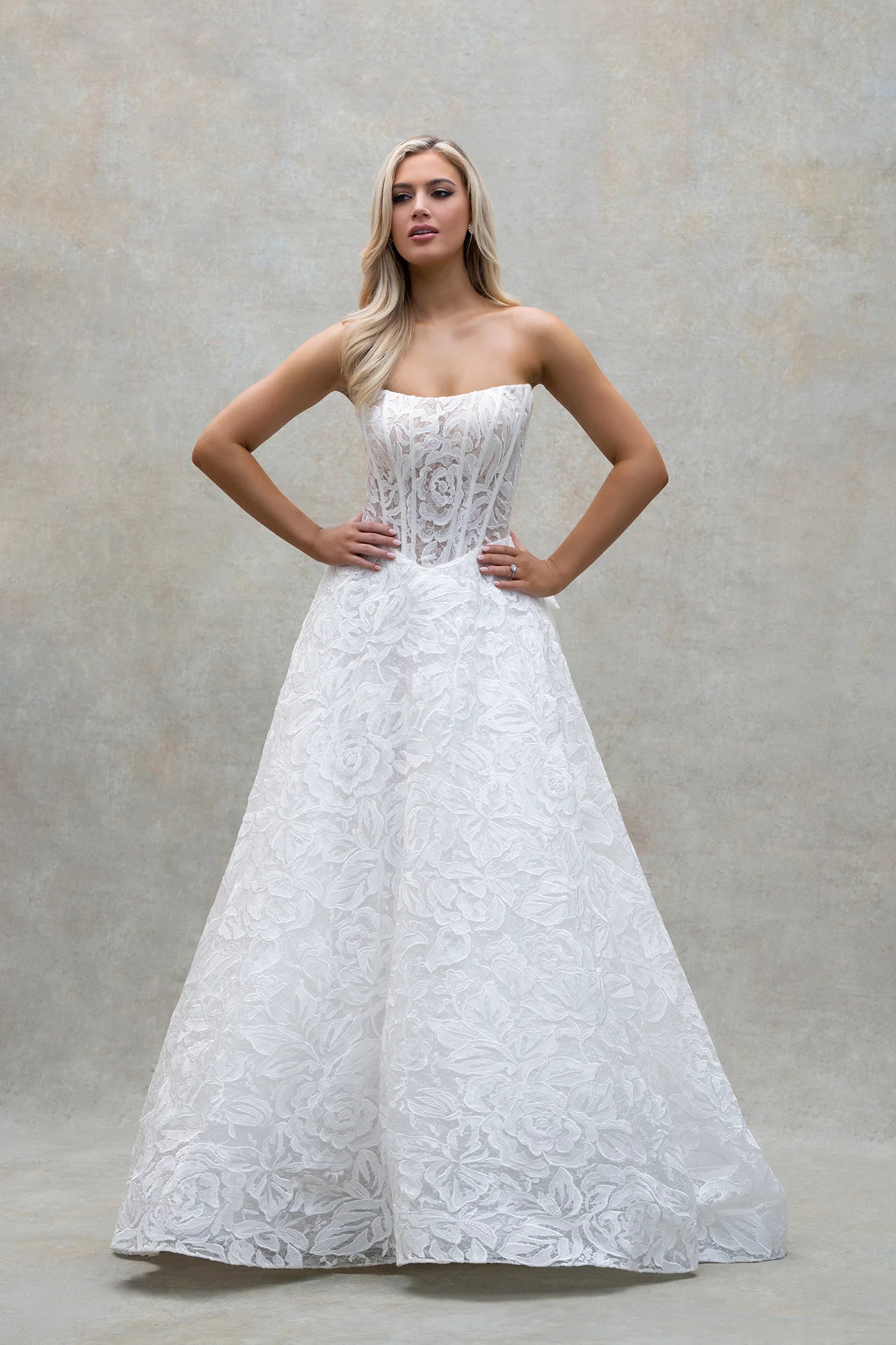 Woman wearing a white lace wedding dress against a neutral background