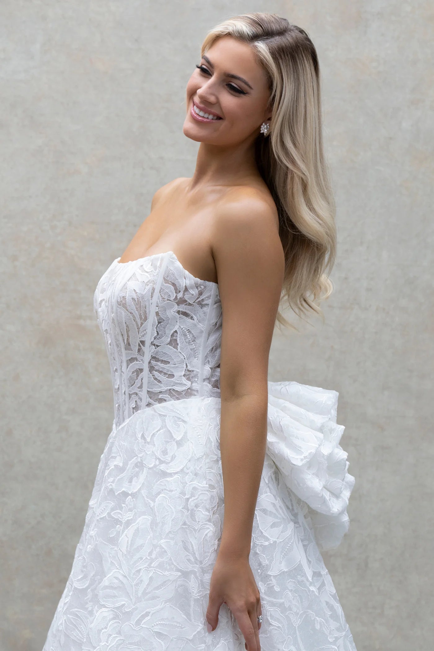 Woman wearing a white lace wedding dress against a neutral background