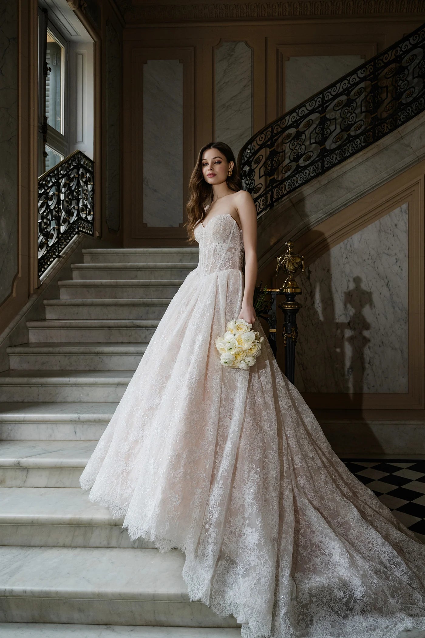 Woman in a wedding dress standing on a staircase in an elegant interior setting
