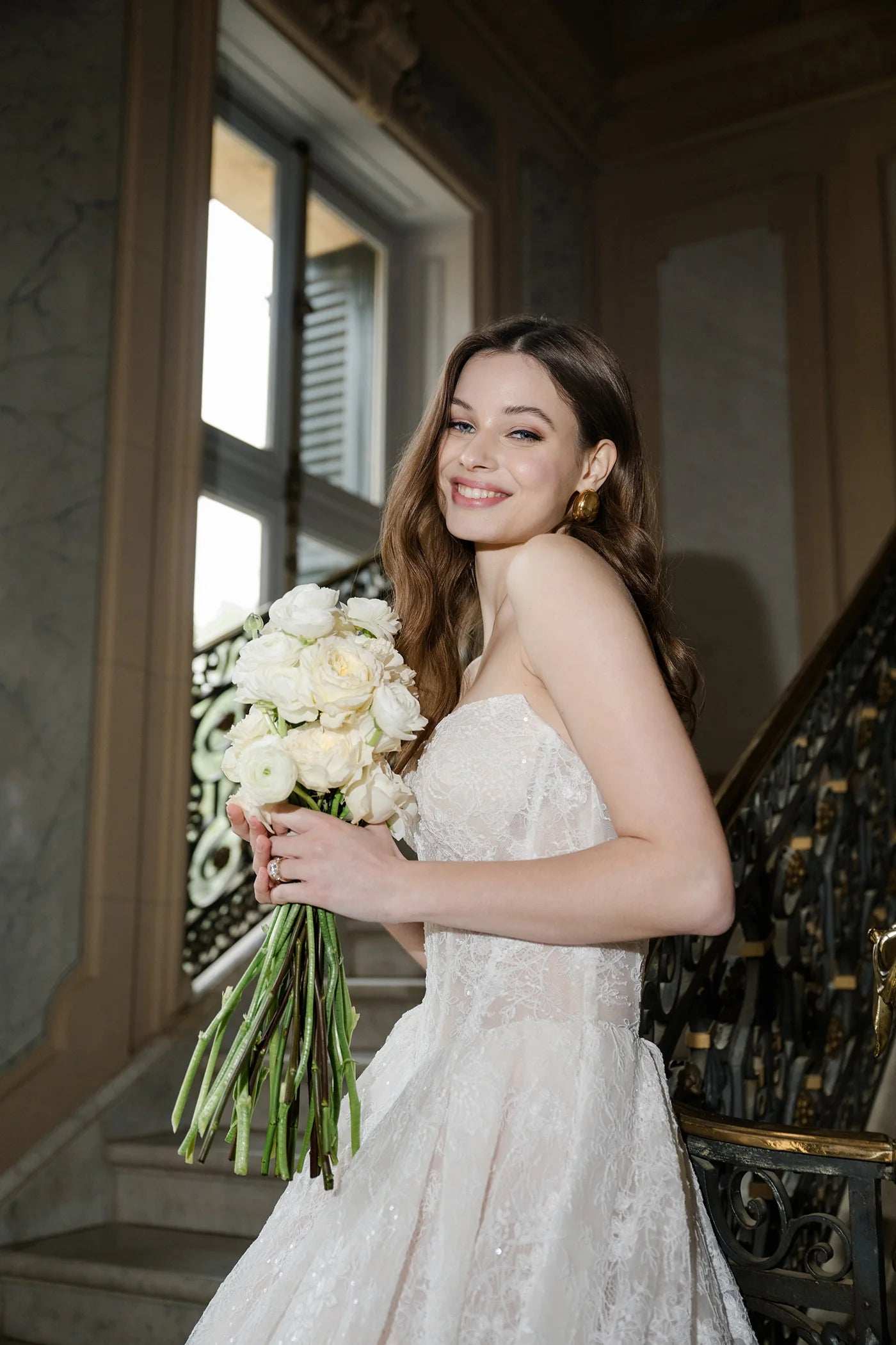 Woman in a wedding dress holding a bouquet of flowers indoors.