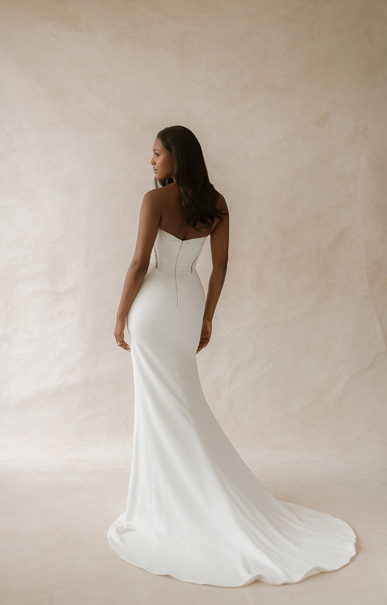 Woman wearing a white wedding dress against a beige background