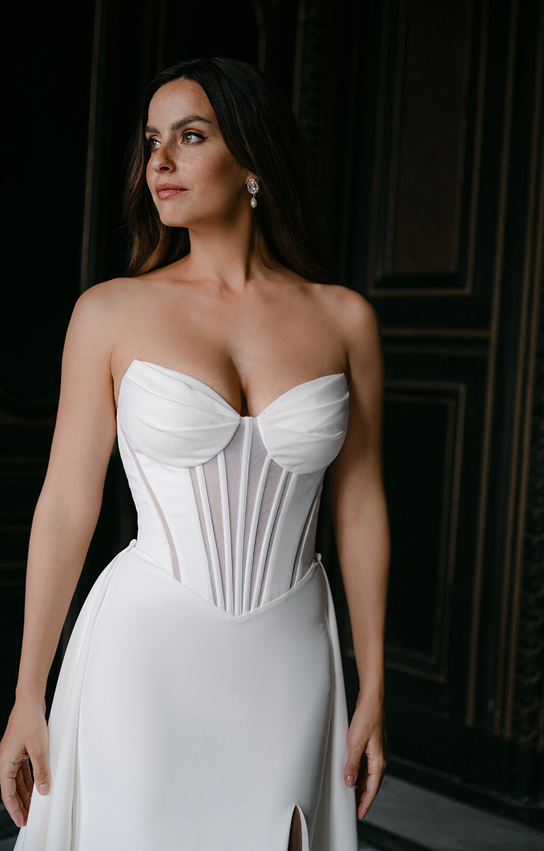 Woman wearing a white strapless gown against a dark background