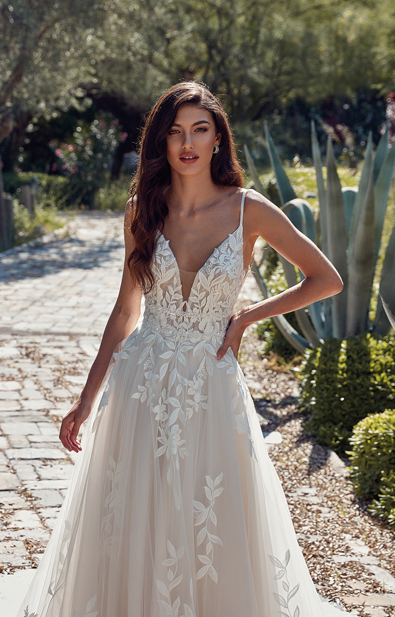 Woman in a white wedding dress standing outdoors with greenery in the background