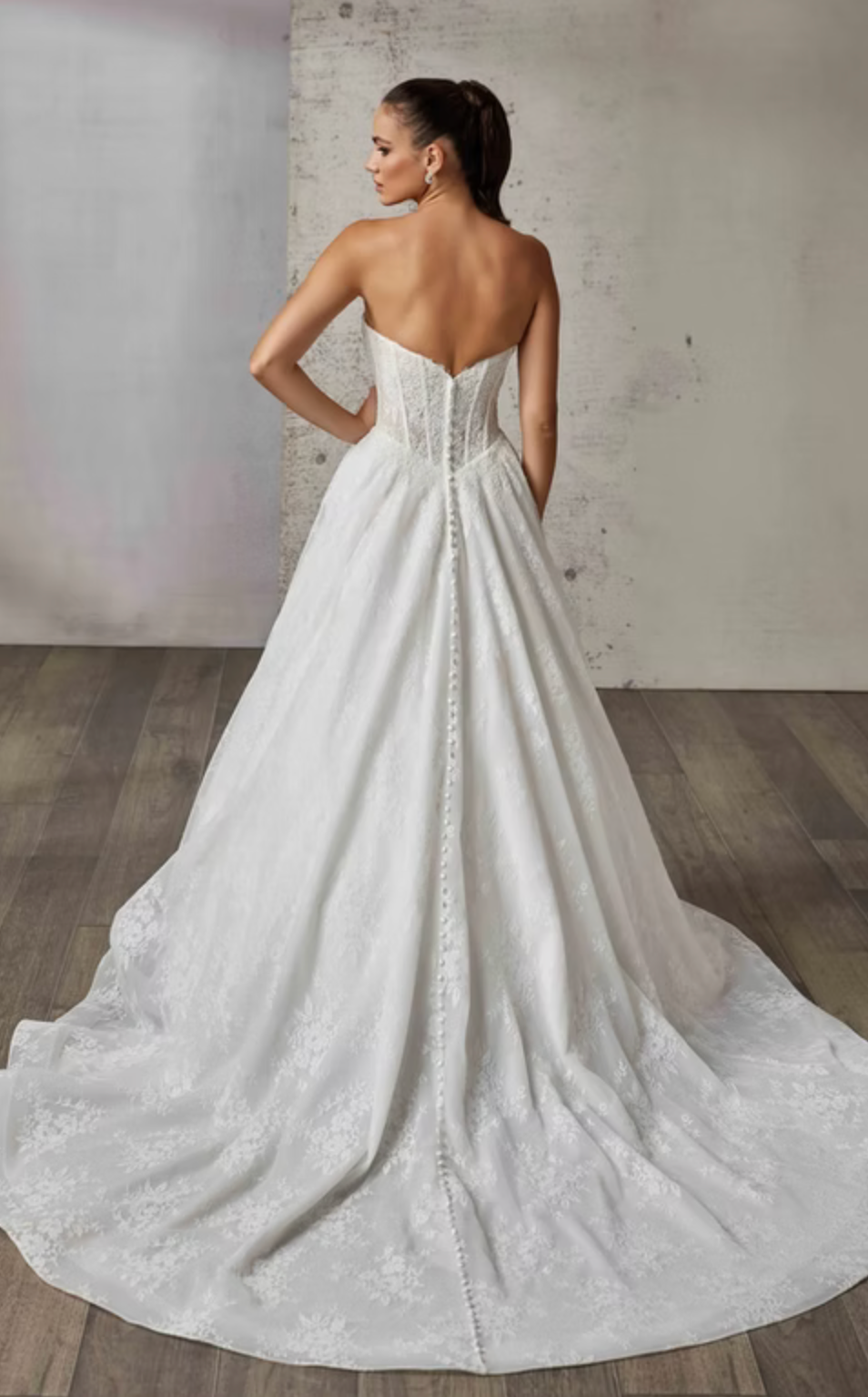 White wedding dress with a long train on a wooden floor.